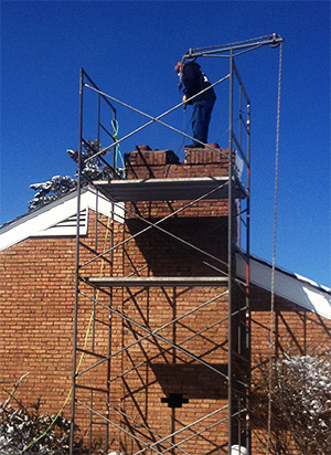 Technician standing on chimney with scaffolding set up next to it