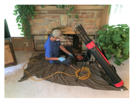 chimney sweep preparing fireplace for sweep service wearing person protective equipment