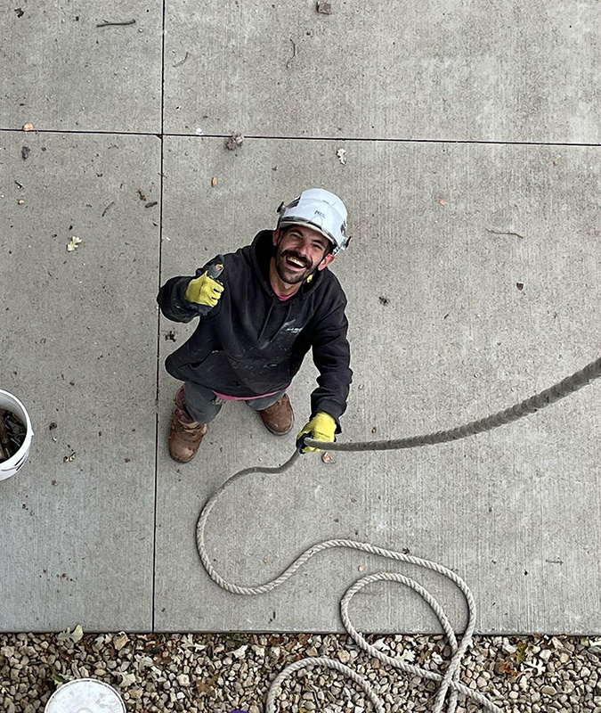 Technician wearing PPE holding a rope and giving a thumbs up